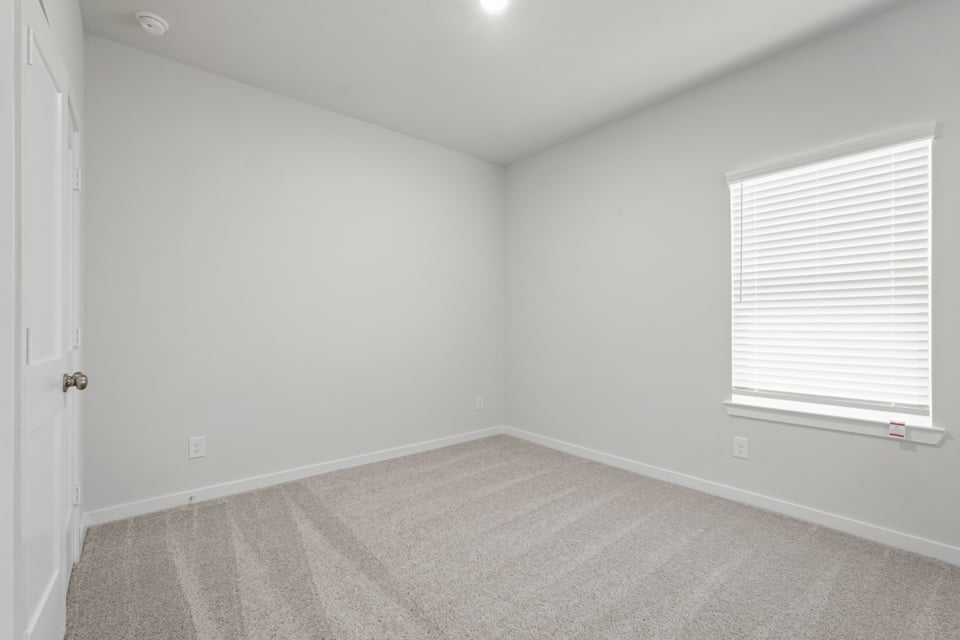 A room with a carpet and a window.