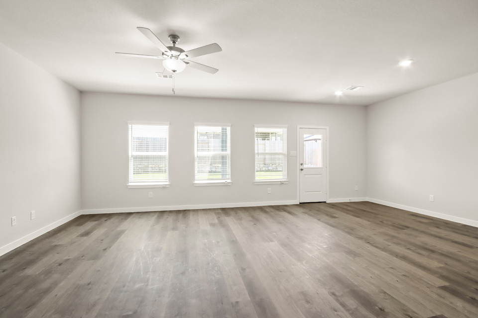 A room with a ceiling fan and a wood floor.