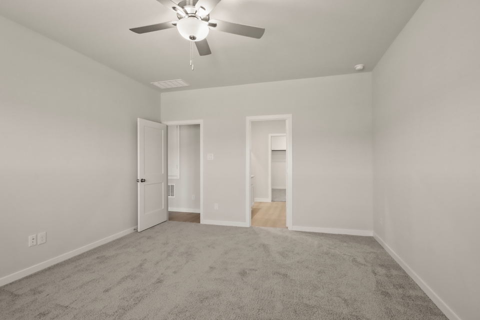 A room with a ceiling fan and a door.