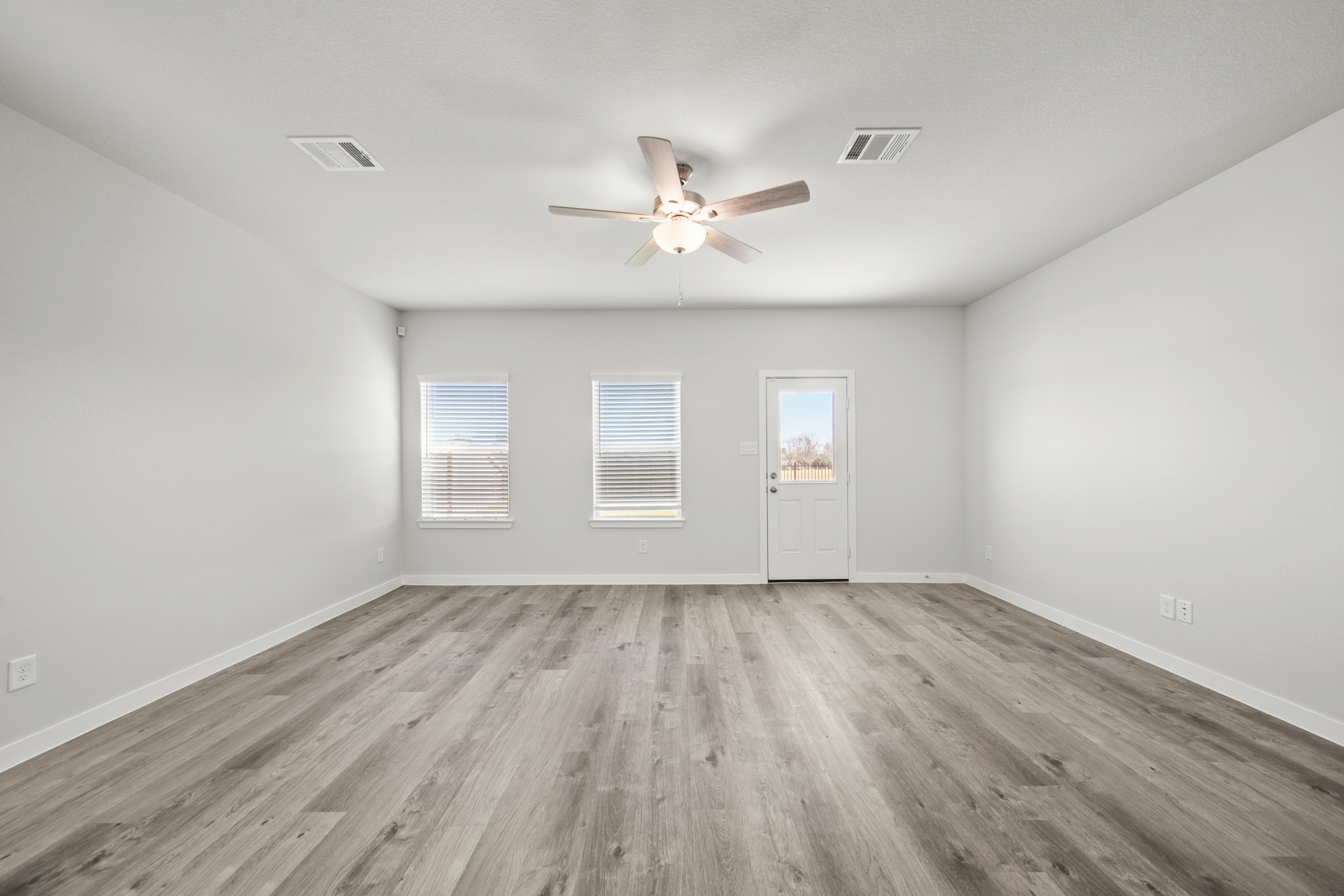 A room with a ceiling fan and wood floor.