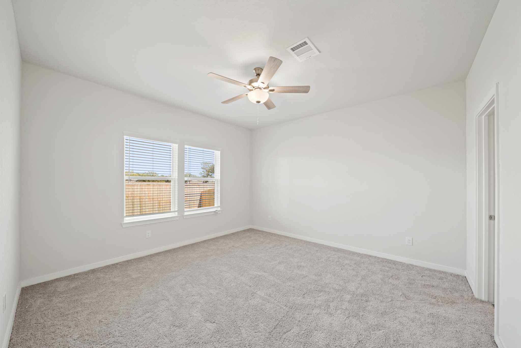 A room with a ceiling fan and a carpet.