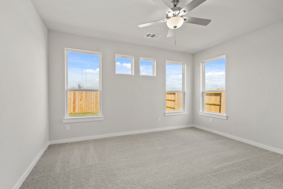 A room with a ceiling fan and windows.