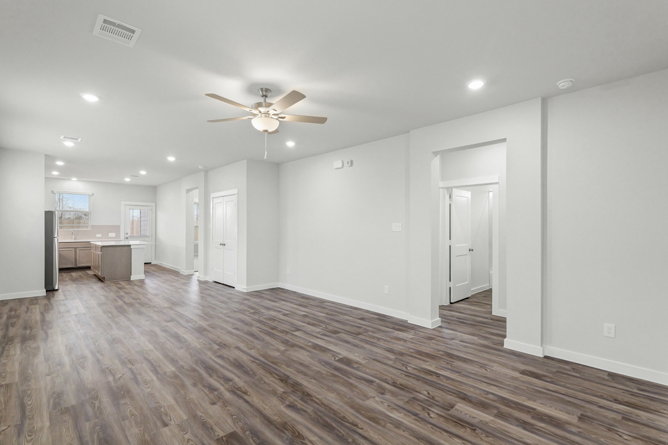 A large empty room with a ceiling fan and a wood floor.