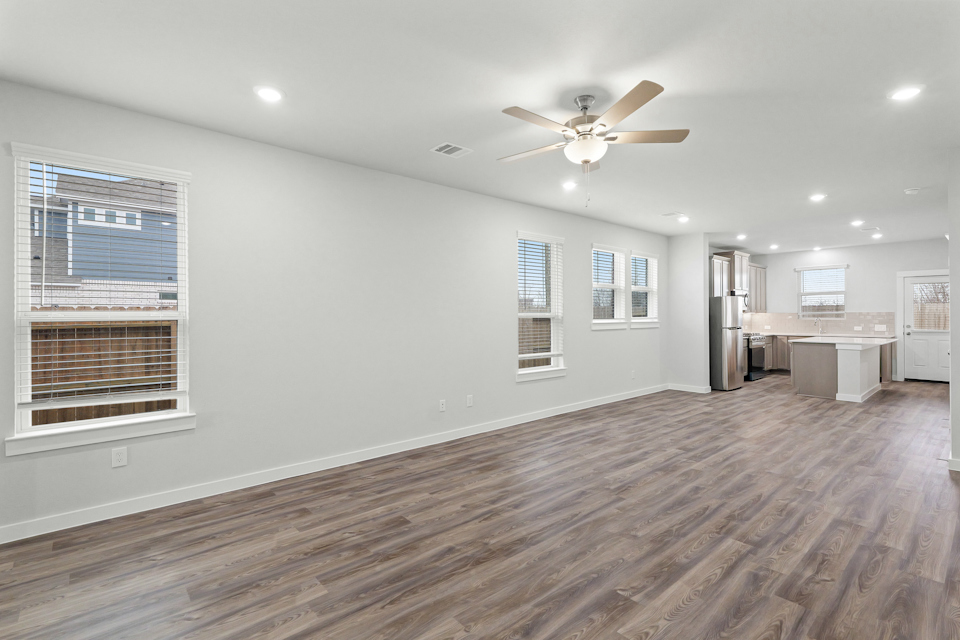 A large empty room with a wood floor and a ceiling fan.