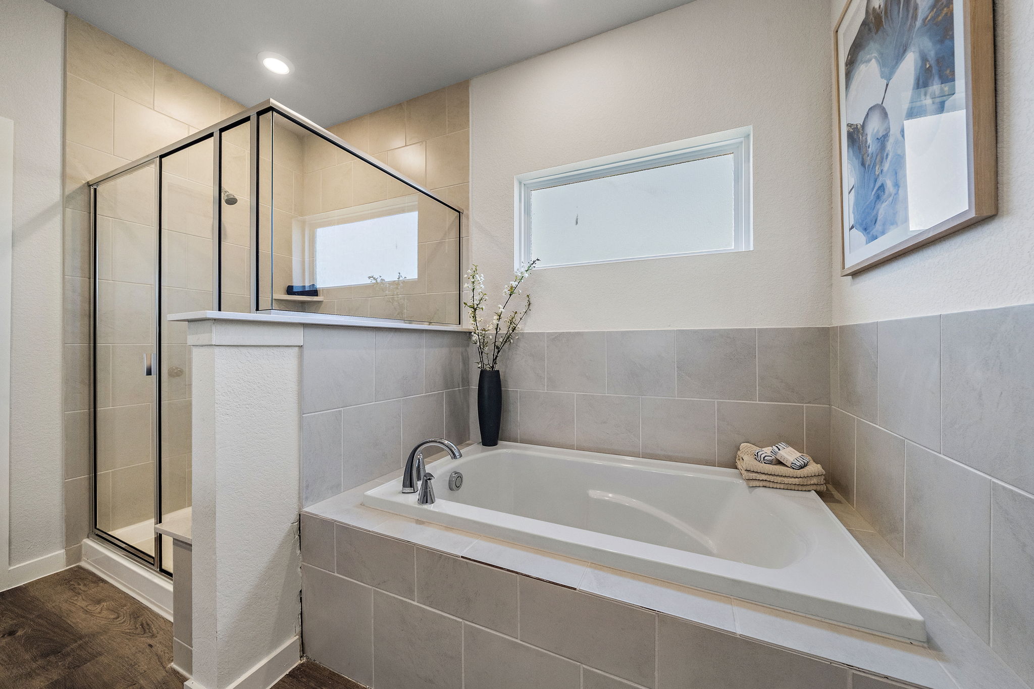 A bathroom with a tub and a vase of flowers.
