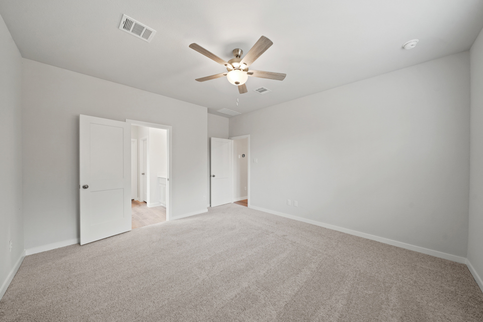 A room with a ceiling fan and white walls.