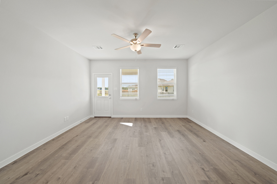 A room with a ceiling fan and a wood floor.