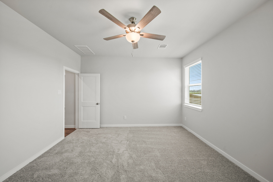 A room with a ceiling fan and a door.