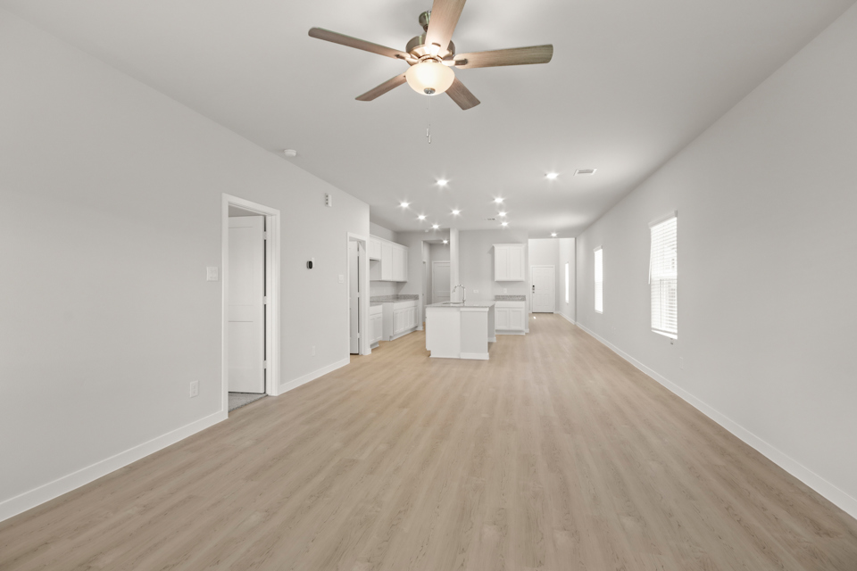 A large empty room with a ceiling fan and white walls.
