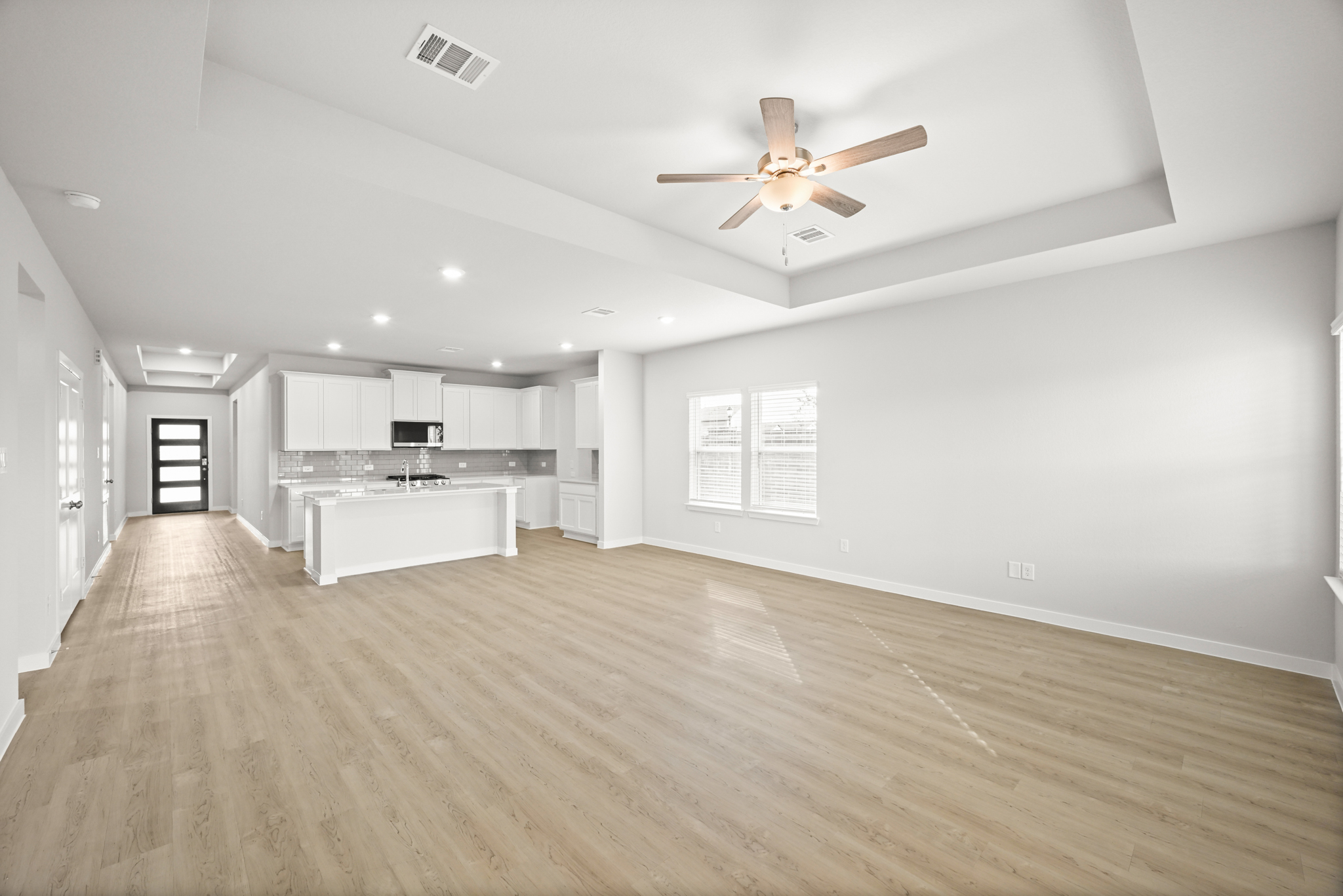 A large empty room with a wood floor and a ceiling fan.