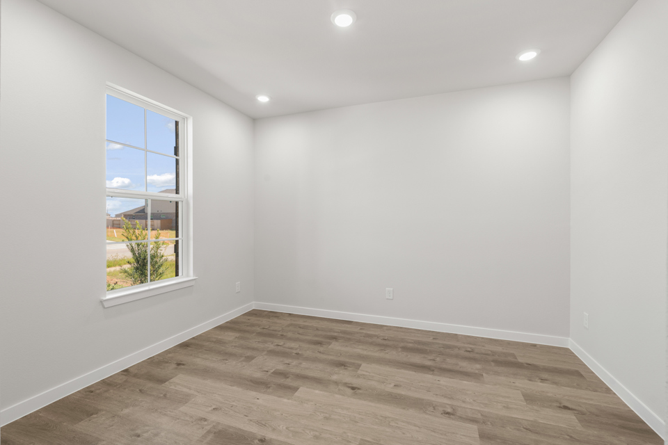 A room with a wood floor and a window with a view of a city.