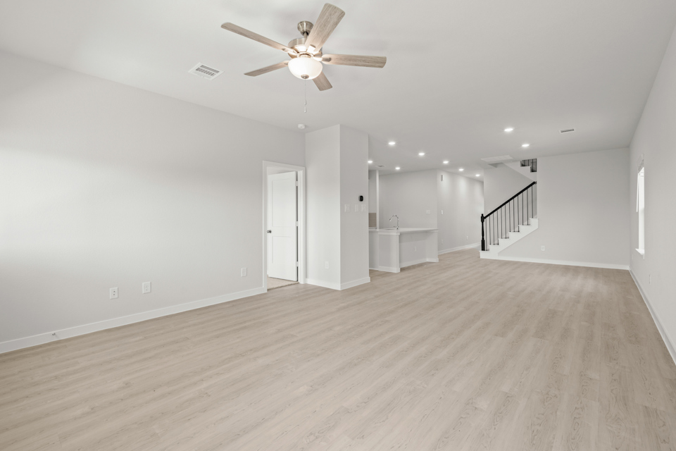 A large empty room with a ceiling fan and a wood floor.