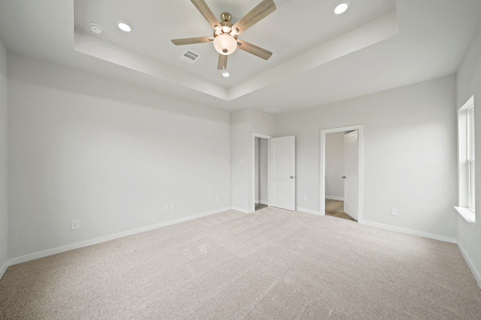A room with a ceiling fan and white walls.