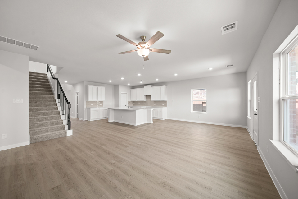 A large empty room with a wood floor and a ceiling fan.