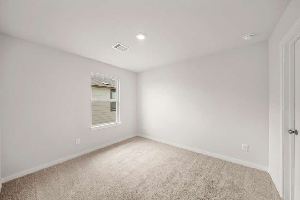 A room with a carpet and a window.