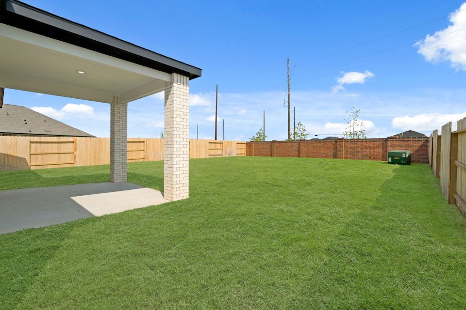 A green lawn with a brick wall and a building in the background.
