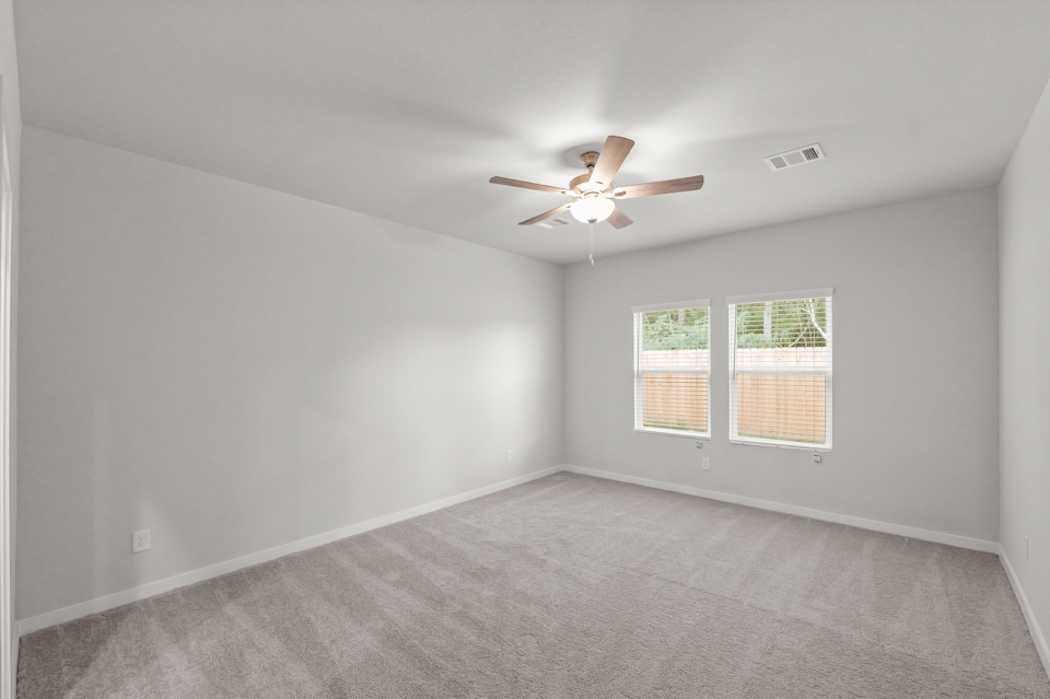 A room with a ceiling fan and a carpet.