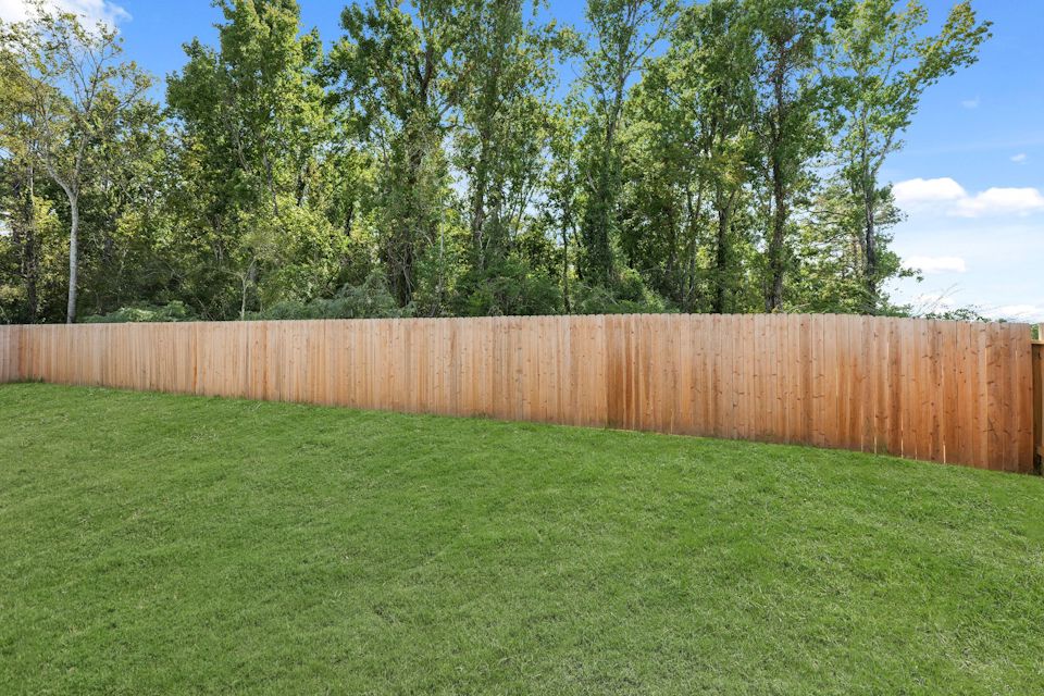 A fenced in yard with trees in the background.