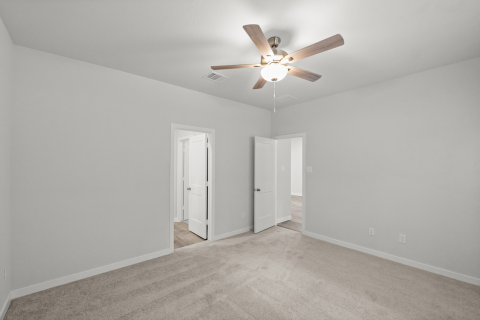 A room with a ceiling fan and white walls.