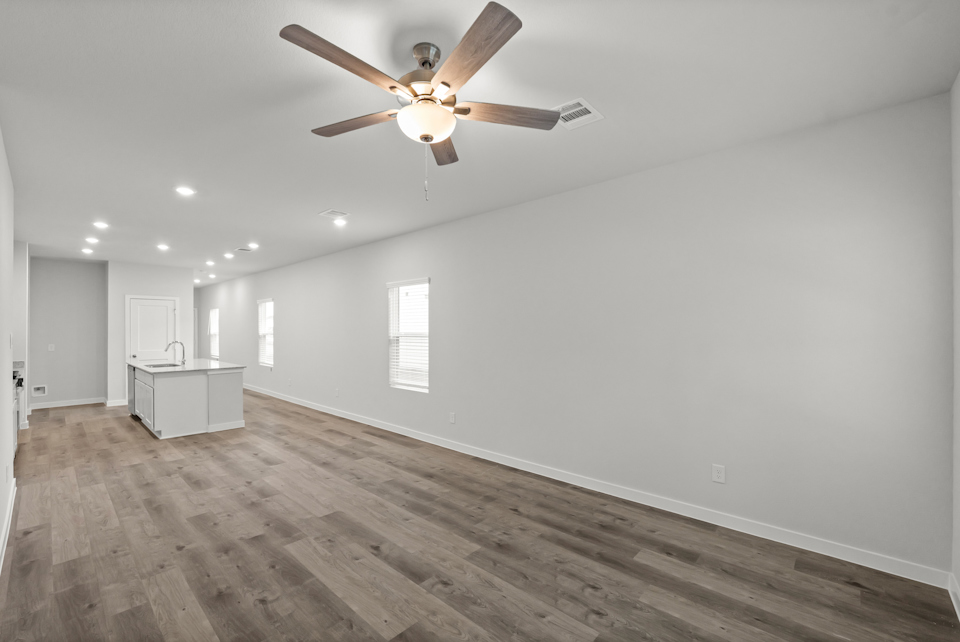 A room with a ceiling fan and a wood floor.