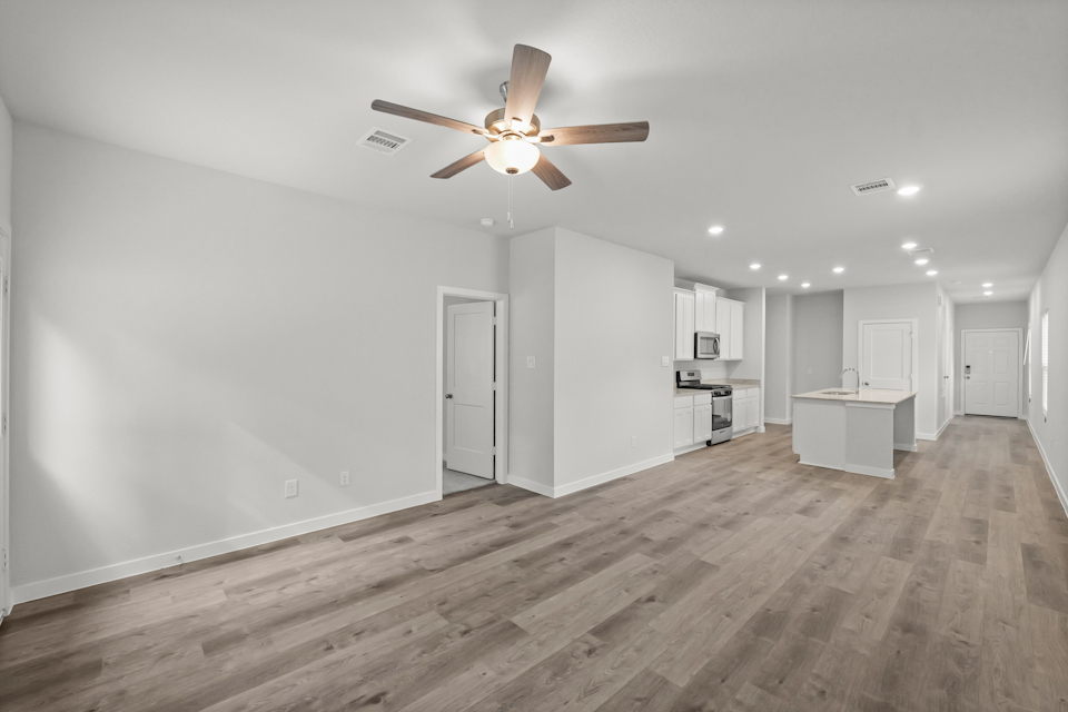 A room with a ceiling fan and white cabinets.