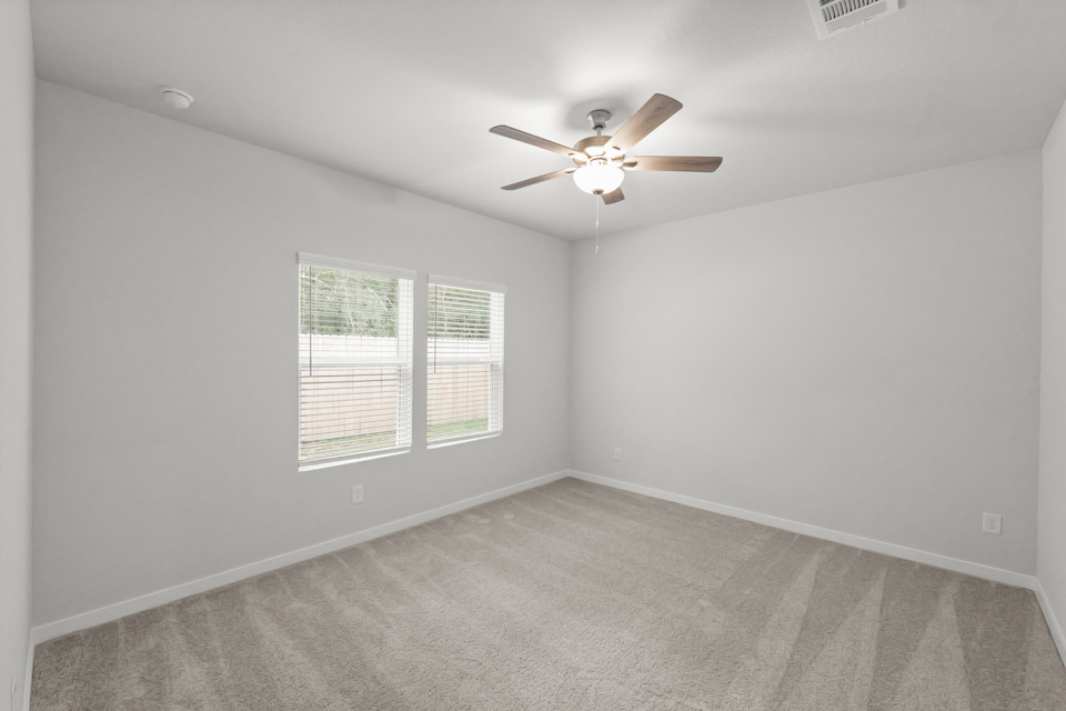 A room with a ceiling fan and a window.