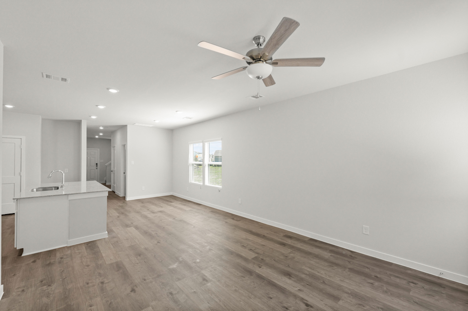 A large empty room with a ceiling fan and a wood floor.