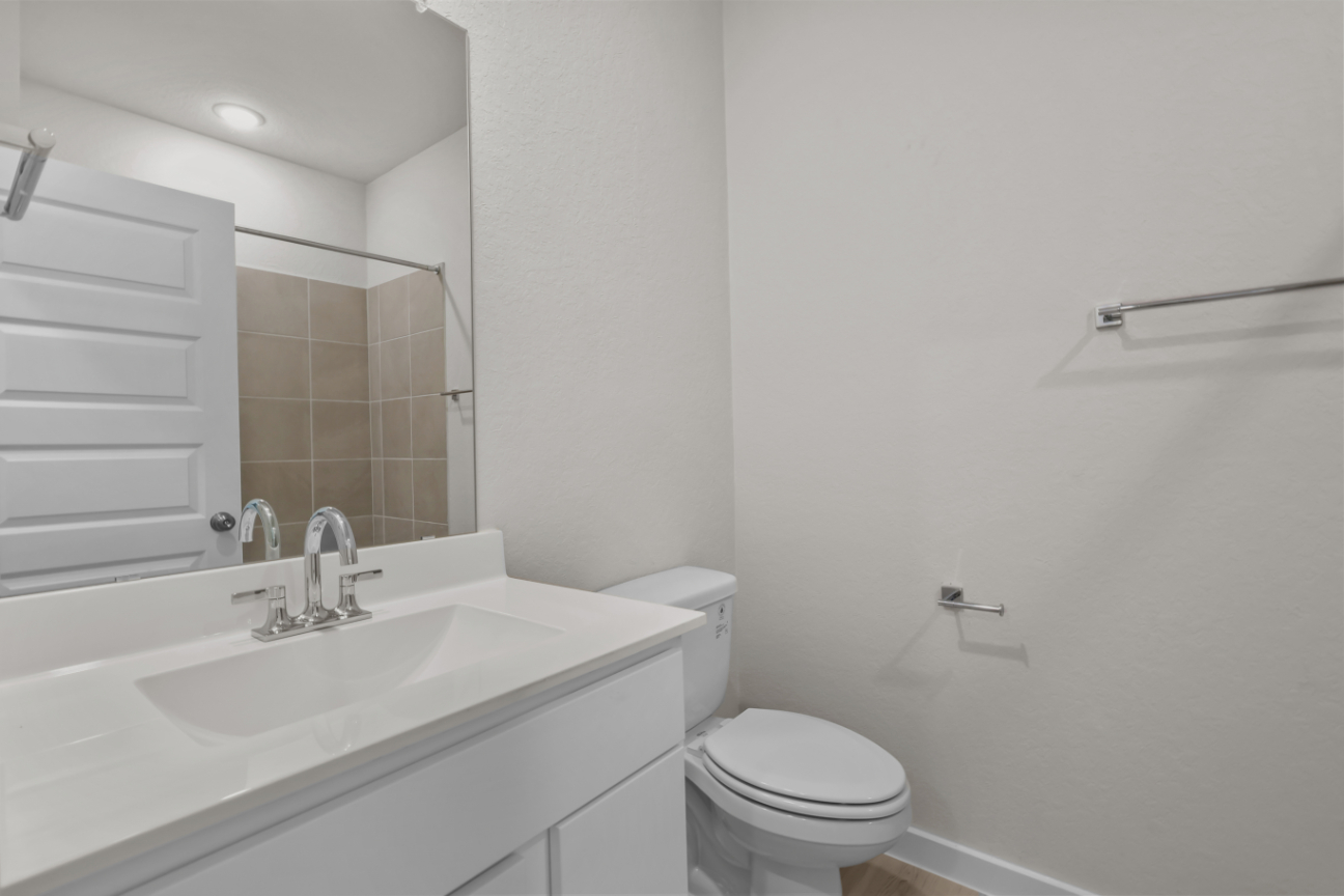 A bathroom with a sink toilet and mirror.