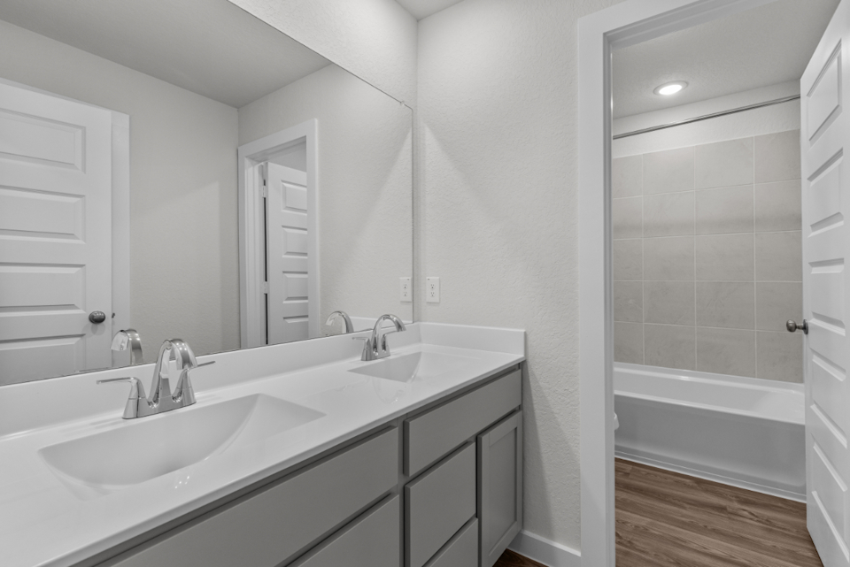 A bathroom with a tub sink and a mirror.