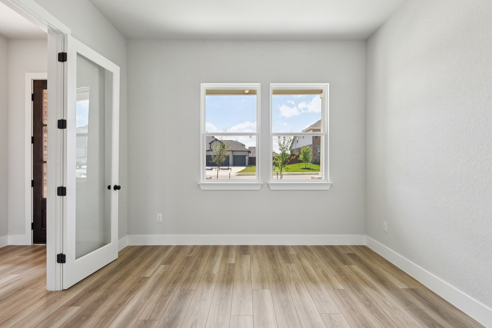 A room with a wood floor and a window with a view of the ocean.