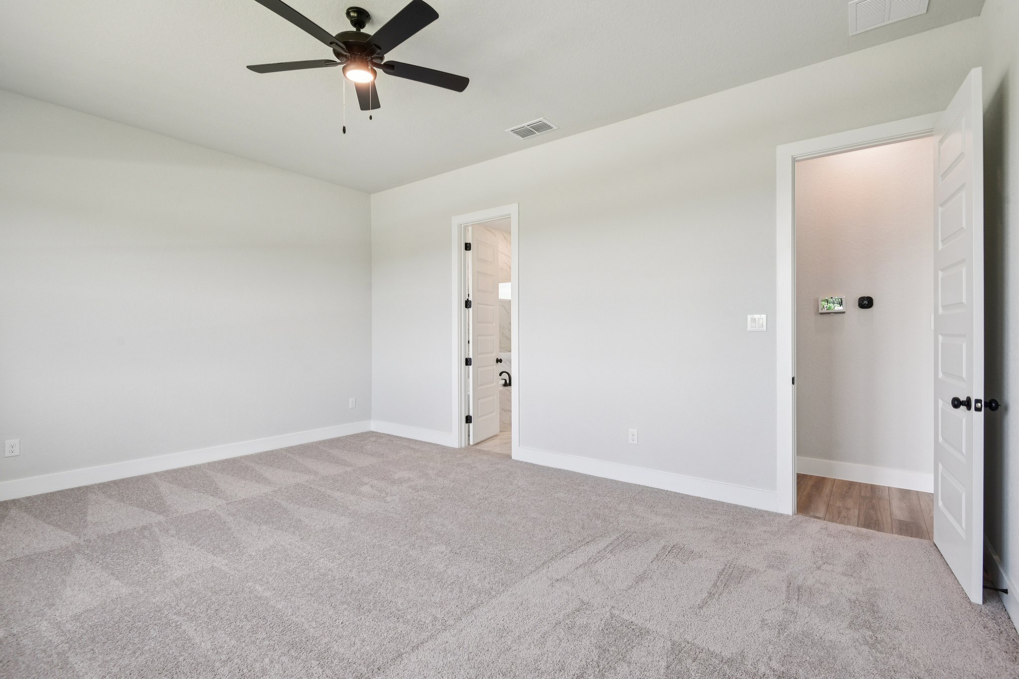 A room with a ceiling fan and white doors.