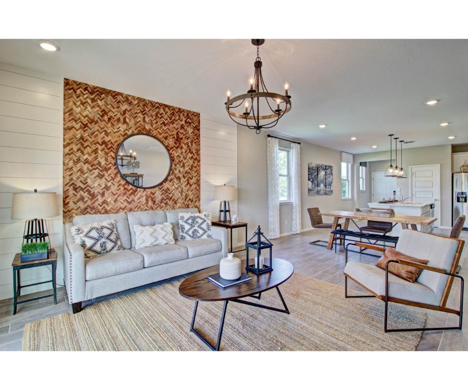 A living room with a large stone wall and a large round mirror.