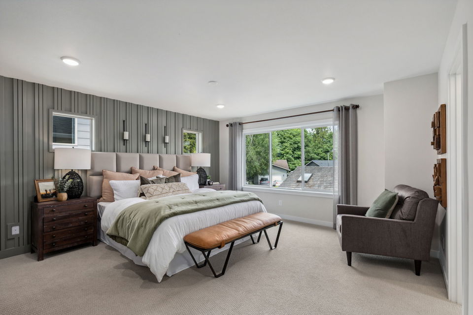 A bedroom with a bed and a chair.