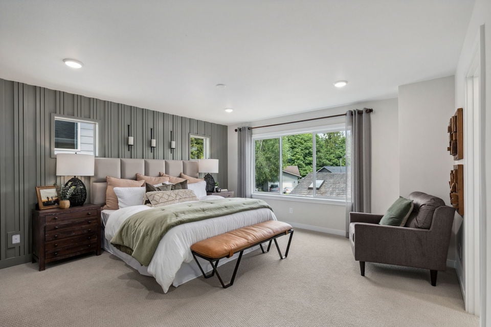 A bedroom with a bed and a chair.