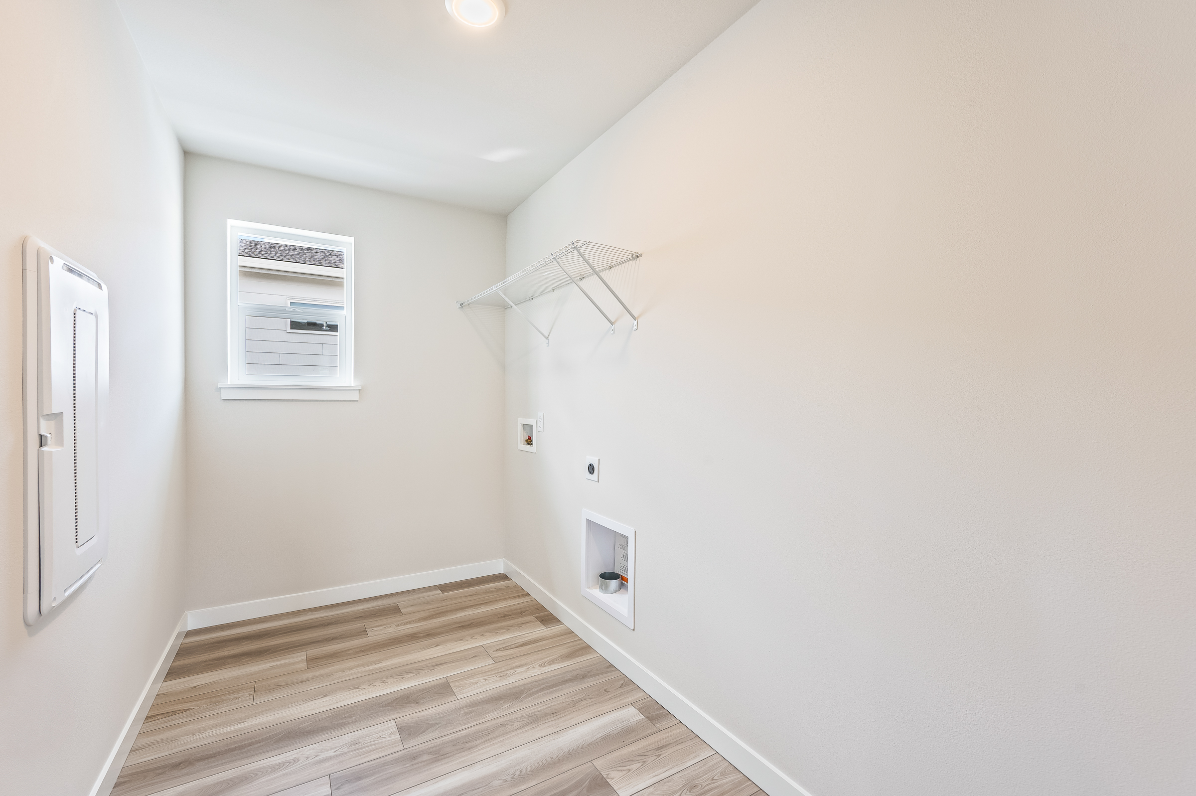 A hallway with a rug and a light on the wall.