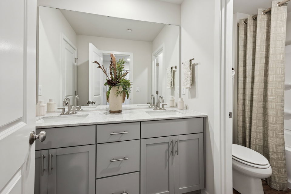 A bathroom with a sink toilet and a mirror.