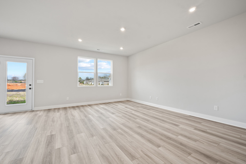 A room with a wood floor and a window with a view of a field and a field.