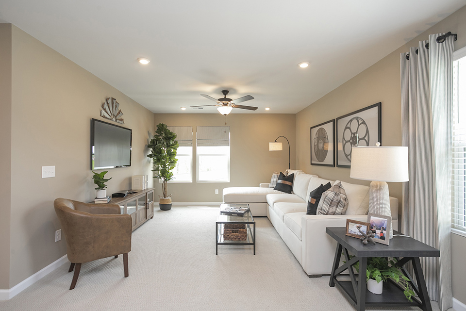 A living room with a white couch and a tv.