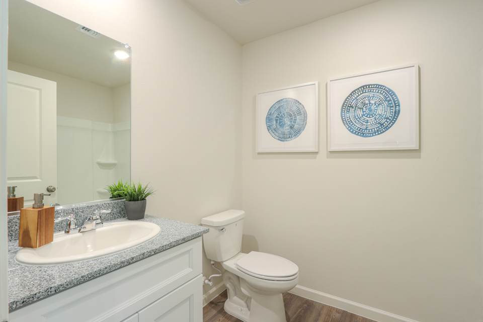 A bathroom with a sink toilet and a mirror.