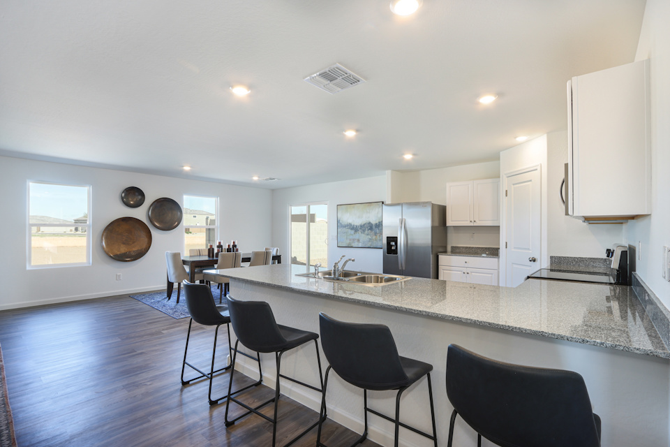 A kitchen with a bar and chairs.