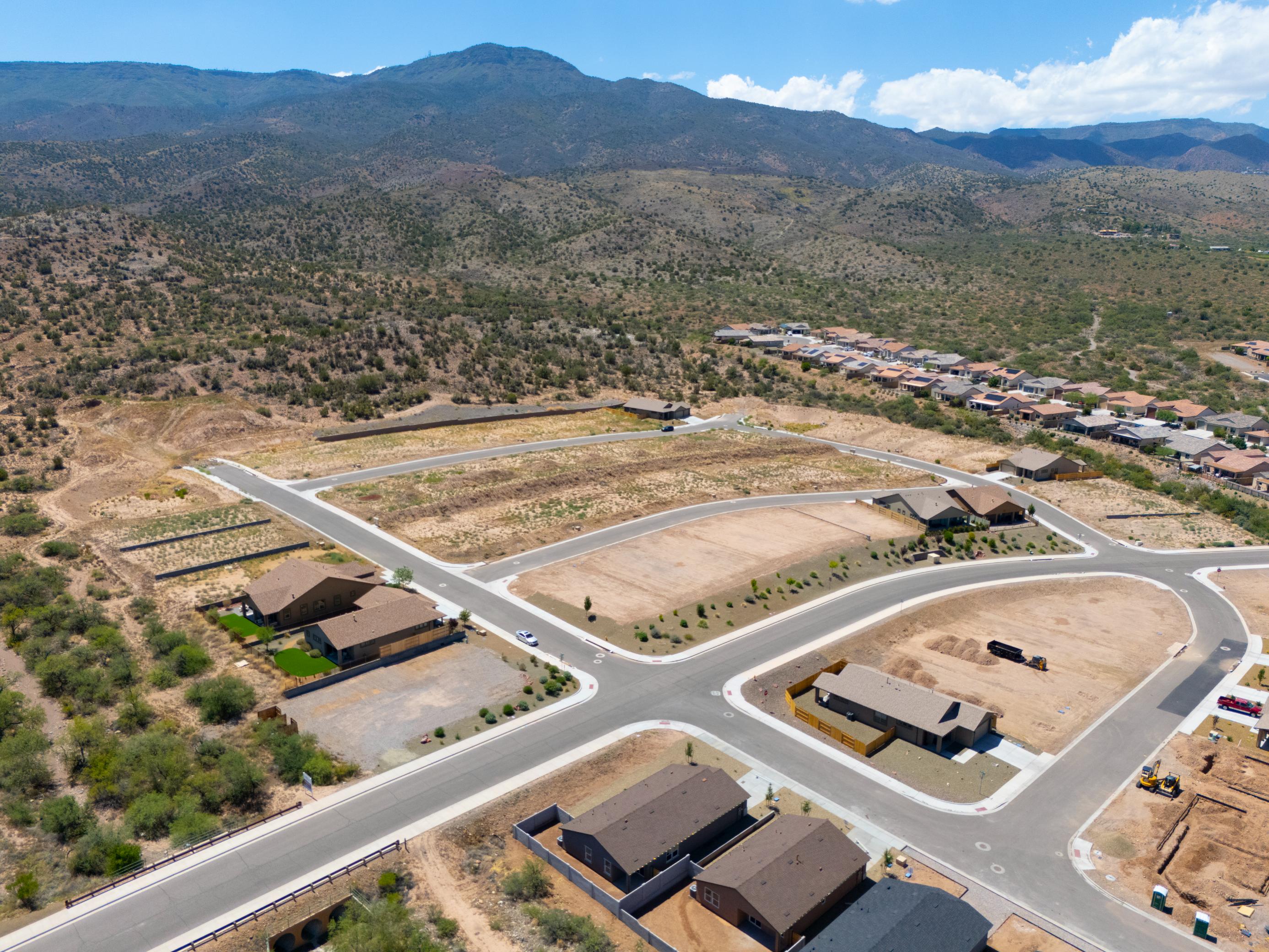 A large white building with a parking lot and trees in the background.