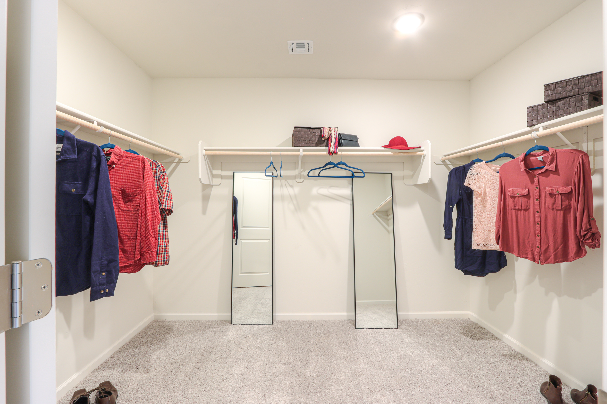A room with a closet and clothes on the wall.