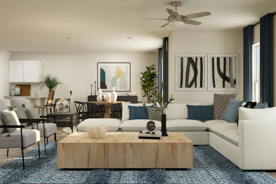 A living room with a large white couch and a table with a plant.