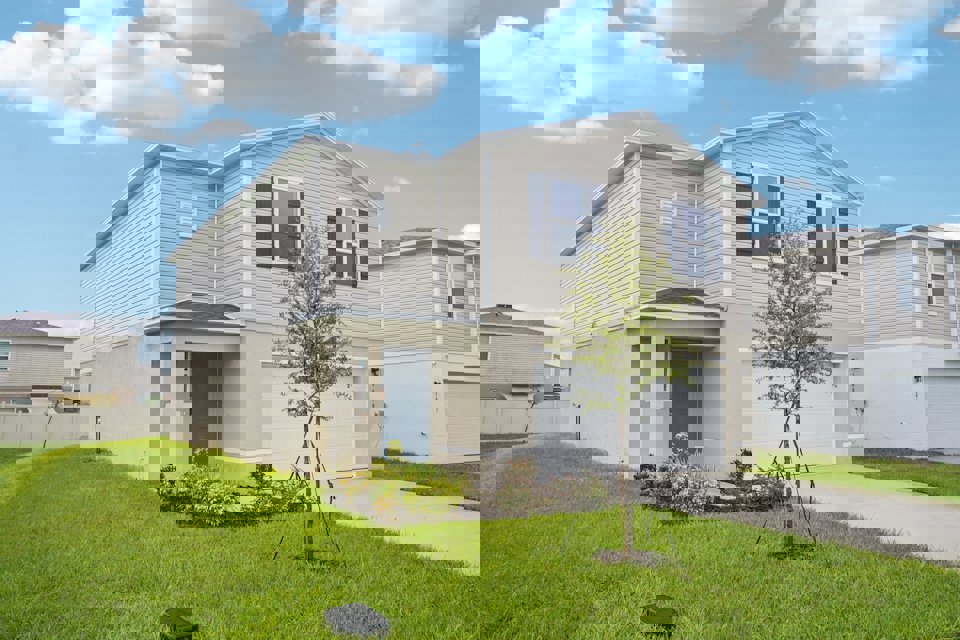 A white house with a tree in the front yard.