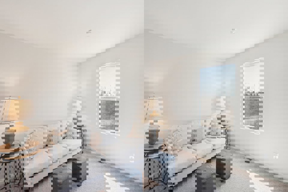 A living room with a white couch and a window.