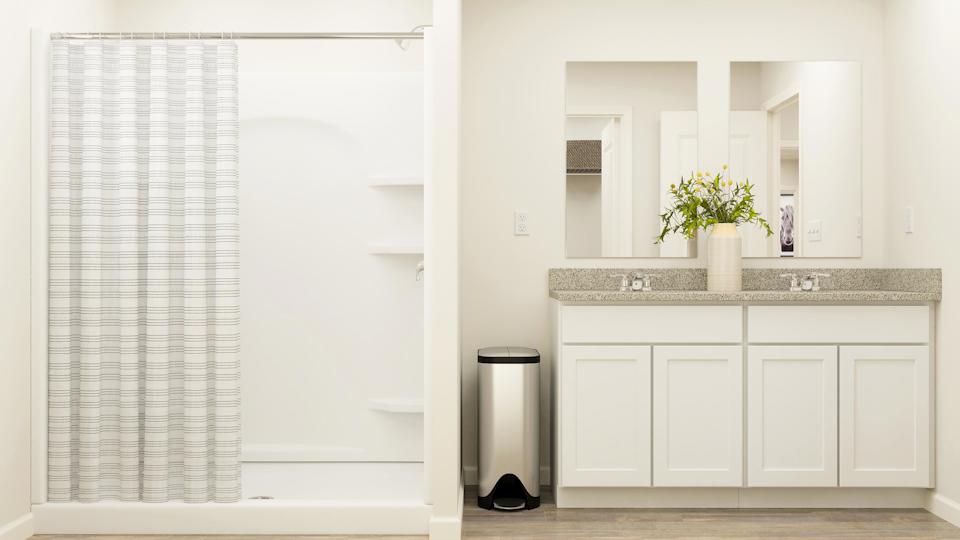 A white kitchen with a black trash can and a white cabinet.