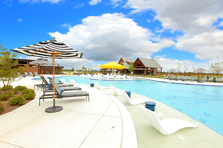 A pool with lounge chairs and umbrellas by it.